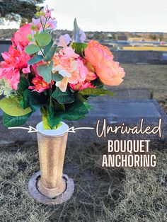 a vase filled with flowers sitting on top of a wooden table next to a grave