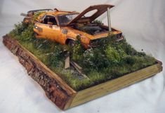 an old car that is sitting on top of a wooden box with grass growing out of it