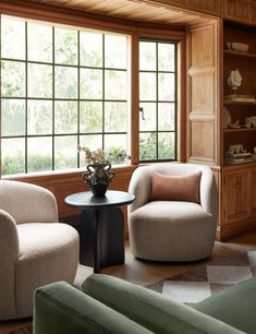 a living room filled with furniture next to a window covered in wooden paneling and windows