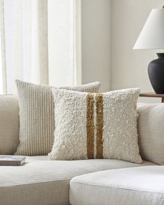 a white couch with two pillows and a remote control on the side table in front of it