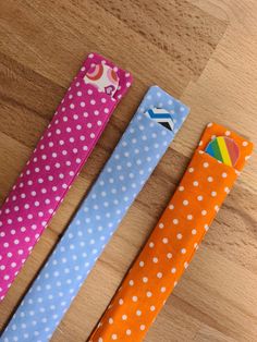 three different colored polka dot ties on a wooden surface with one tied to the other