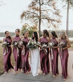 a group of women standing next to each other wearing dresses and holding bouquets in their hands