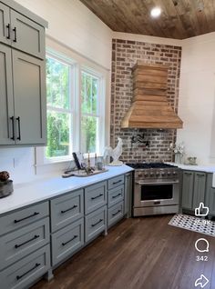 a kitchen with gray cabinets and an oven in the center, surrounded by wood flooring