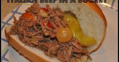 a close up of a sandwich on a plate with words above it that reads italian beef in a bun