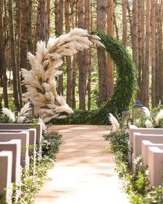 an outdoor ceremony setup with white flowers and greenery on the aisle, surrounded by rows of pews