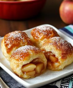 two pastries on a plate with apples in the background