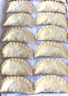 eight uncooked pastries sitting on top of a baking sheet covered in wax paper