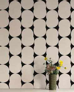 a vase filled with yellow flowers sitting on top of a table next to a wall