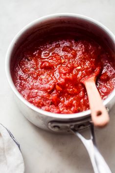 a white bowl filled with red sauce and a wooden spoon on top of the bowl