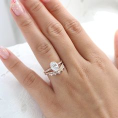 a woman's hand with two wedding rings on her left and the other hand holding an engagement ring