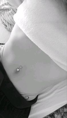 black and white photograph of a woman's stomach with a single piercing on it