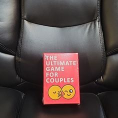 the ultimate game for couples sits on top of a black leather chair with two emoticions