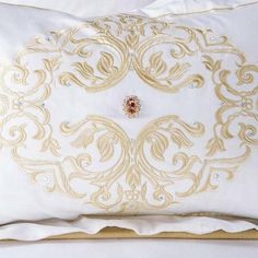 a white and gold pillow on top of a bed