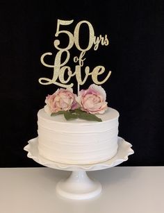 a white cake topped with pink flowers and the words 50 days of love on top