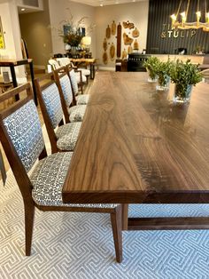 a dining room table with chairs and plants in vases on the top, along with other furniture