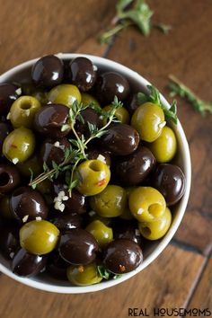 a white bowl filled with olives on top of a wooden table