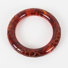 This is part of Chairish’s Costume Jewelry assortment.  Stunning red tea amber marble Bakelite bracelet bangle. Chunky rounded domed shape with a deep floral carving all around. Intense orange-red color with lots of cloudy swirling and translucency. Measurements: Inside across is 2.50 in diameter (6.4 cm) - outside across is 3.63 in diameter (9.2 cm) - width is 0.57 in wide (1.4 cm) - the wall is 0.57 in thick (1.4 cm).  Please see the measurements noted above in the description for the best app Elegant Tortoiseshell Bangle Jewelry, Luxury Red Bangle, Elegant Bakelite Bangle As Gift, Elegant Bakelite Bangle As A Gift, Luxury Carved Bangle Bracelets, Luxury Carved Bangle Bracelet, Formal Brown Round Bangle, Brown Bakelite Bangle Bracelet, Elegant Bakelite Bracelet Jewelry