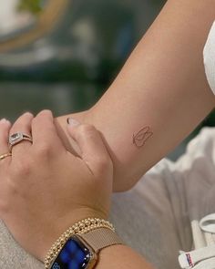 a woman's arm and wrist with a small tattoo on the left side of her hand