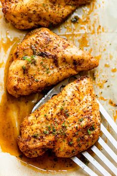 two pieces of chicken sitting on top of a pan