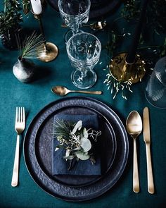 a place setting with silverware and greenery