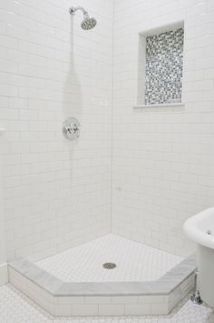 a white tiled bathroom with a walk in shower