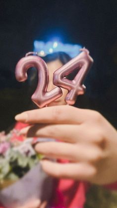 a woman holding up the number twenty four in front of her face