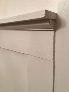 the corner of a wall with a white paint job on it's side and an unfinished piece of wood sticking out from underneath