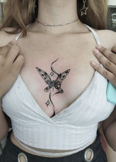 a woman with a butterfly tattoo on her chest holding a toothbrush in her right hand