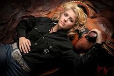 a beautiful blond woman laying on top of a brown leather chair next to a cowboy boot