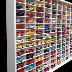 a white shelf filled with lots of toy cars