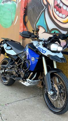 a motorcycle parked next to a wall with graffiti on it