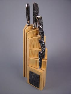 three knives are stuck into the top of a wooden stand with black marble on it