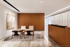 an office with wooden paneling and white chairs in front of a reception desk on one side