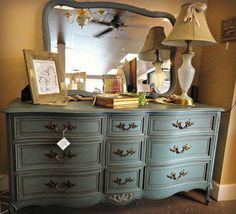 an old dresser has been painted blue with gold hardware, and is adorned with lamps