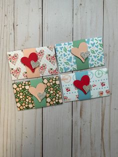 four small cards with hearts on them sitting next to each other in front of a wooden background