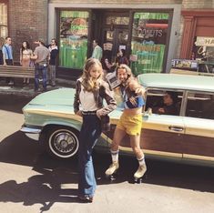 two women are standing next to a car