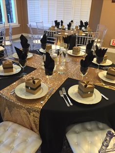 a table set up with black and white plates, silver napkins and gold sequin covered place settings