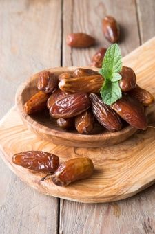 a wooden bowl filled with almonds on top of a cutting board