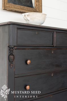 a black dresser with an antique bowl on top