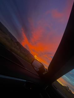 the sun is setting behind some clouds in the sky as seen from inside a car