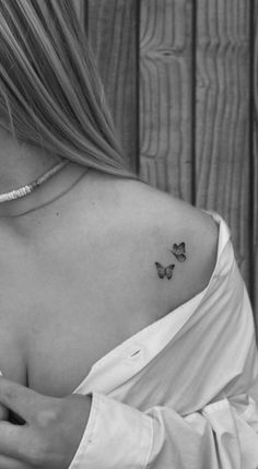 a woman with a small butterfly tattoo on her back shoulder and left arm, in black and white