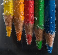 several colored pencils with water droplets on them