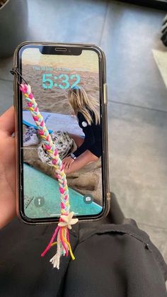 someone holding up their cell phone with a rope attached to it