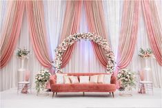 a couch sitting in front of a pink and white stage with flowers on the back