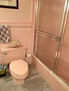 a bathroom with pink walls and tile flooring is pictured in this image, there is a shower stall next to the toilet