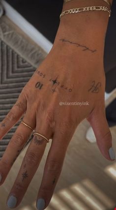 a woman's hand with tattoos on her left wrist and two fingers in the foreground