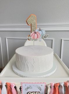 a white cake sitting on top of a table next to pink and orange ribbon decorations