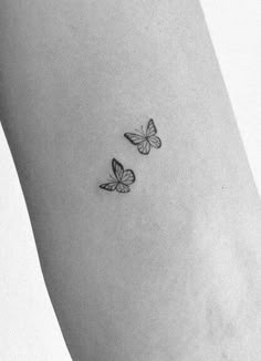 two small butterflies on the left side of the arm, one is black and white