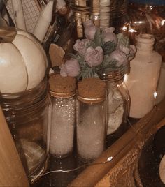 some jars with flowers are sitting on a table next to other items and utensils