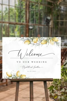 a welcome sign with lemons on it in front of a greenhouse filled with potted plants